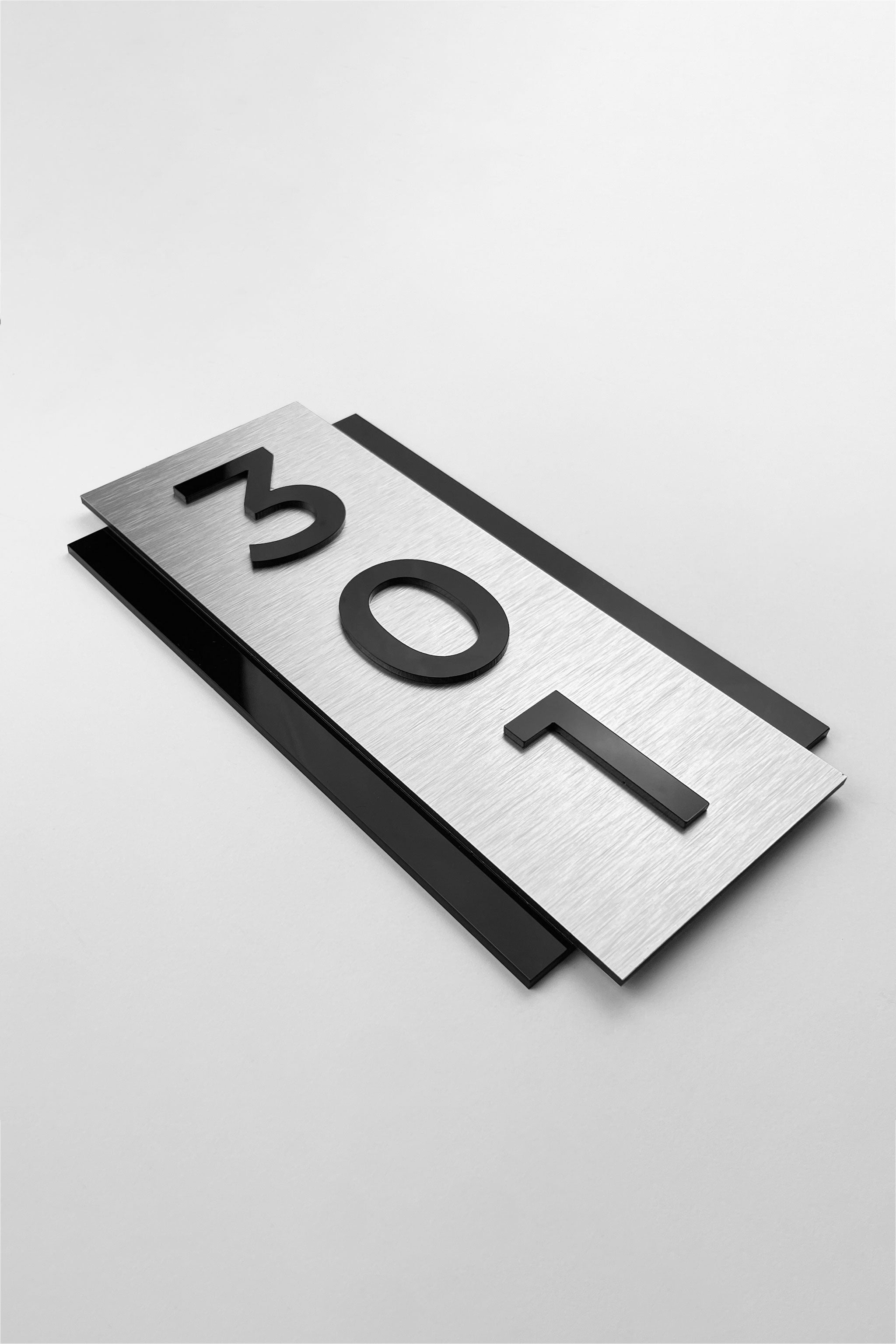 Vertical brushed silver room number sign by ALUMADESIGNCO featuring metal plaque and acrylic numbers, modern wall door signage for hotel corridors and apartment buildings