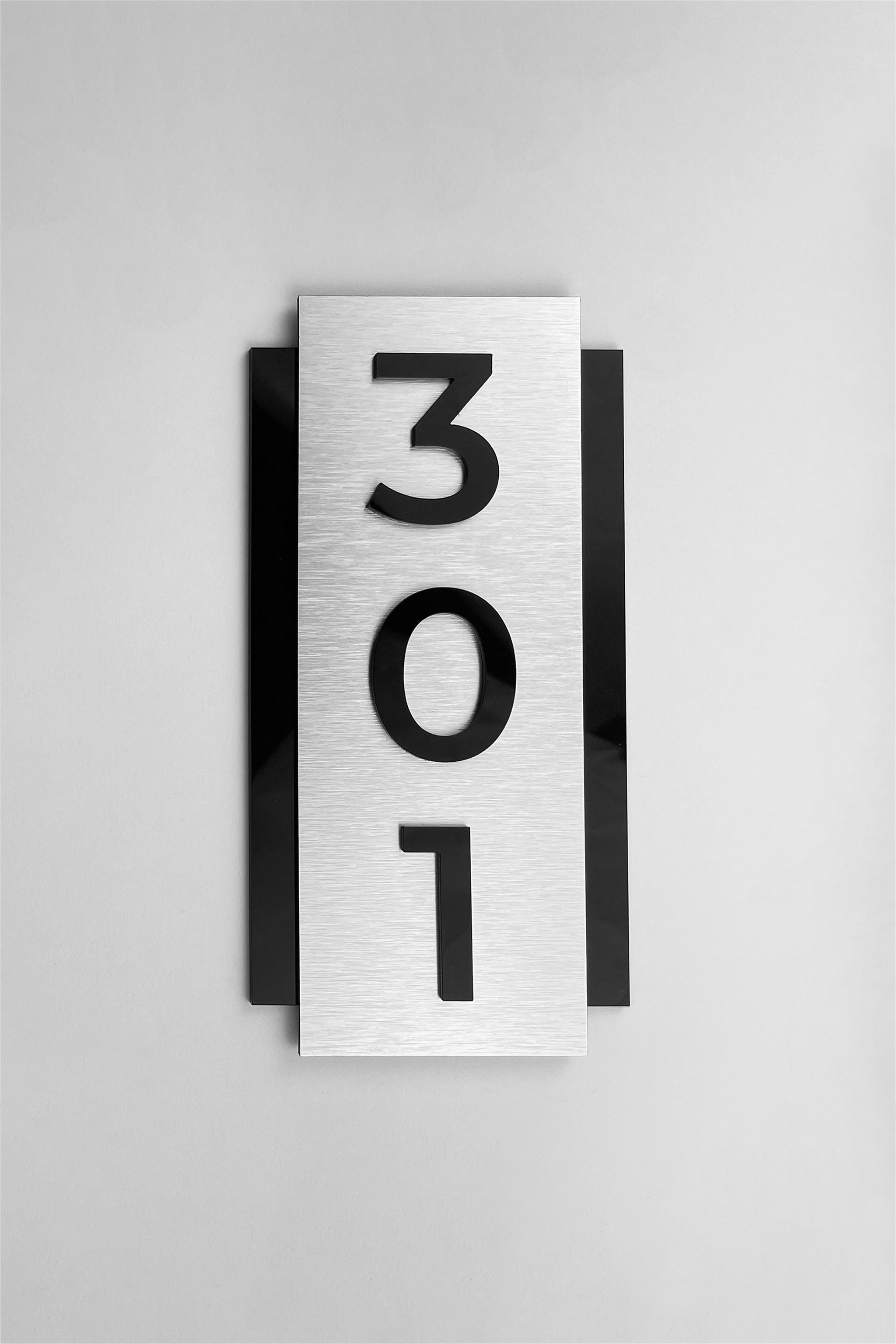 Modern vertical room number sign by ALUMADESIGNCO combining brushed silver aluminum panel and acrylic numbers, elegant wall signage for hotel rooms and apartment doors