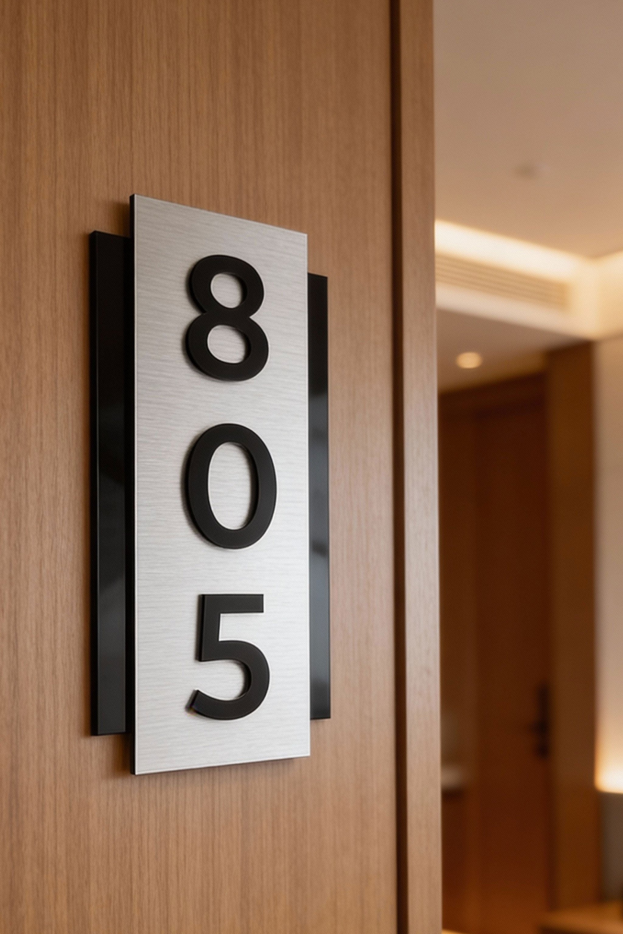 ALUMADESIGNCO modern brushed silver room number sign with raised black acrylic numbers, vertical wall signage for hotels, apartments, and contemporary interiors