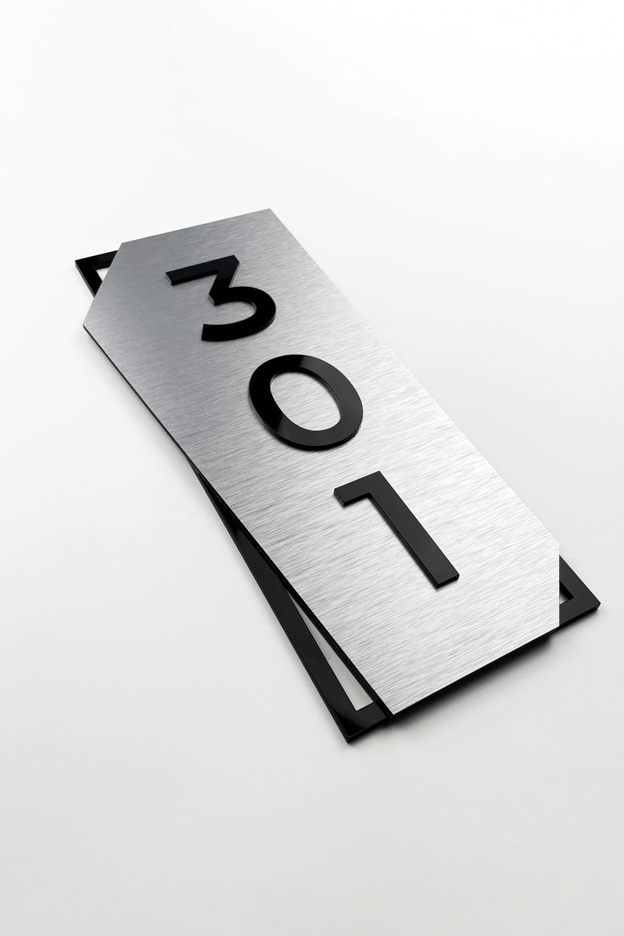 Modern vertical door number sign by ALUMADESIGNCO combining brushed silver metal panel and black acrylic glass numbers, elegant signage for contemporary interiors