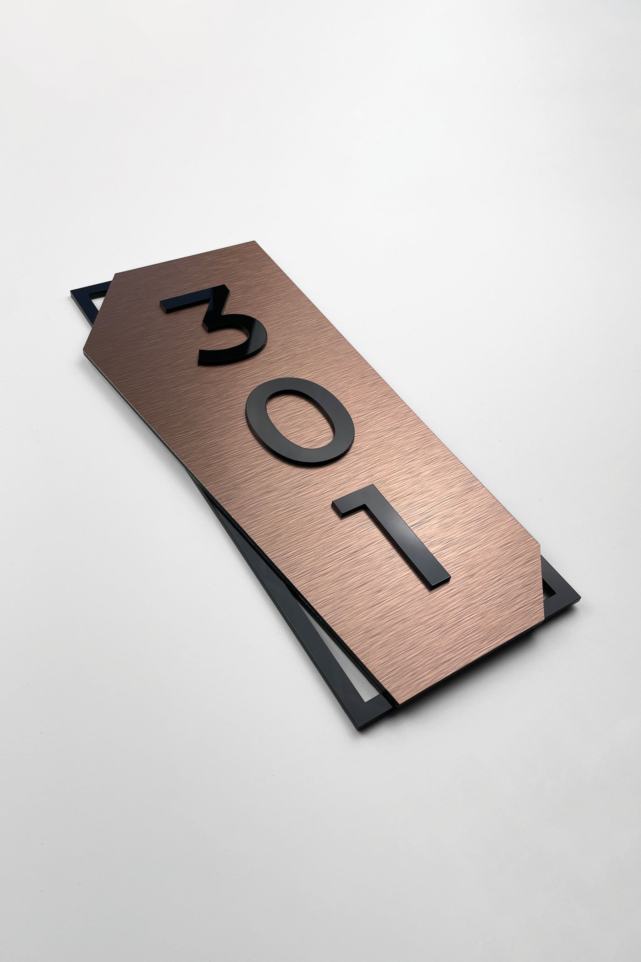 Vertical brushed bronze hotel room number sign by ALUMADESIGNCO featuring bronze aluminum base and black acrylic numbers, modern door number signage for hotel corridors and apartment buildings