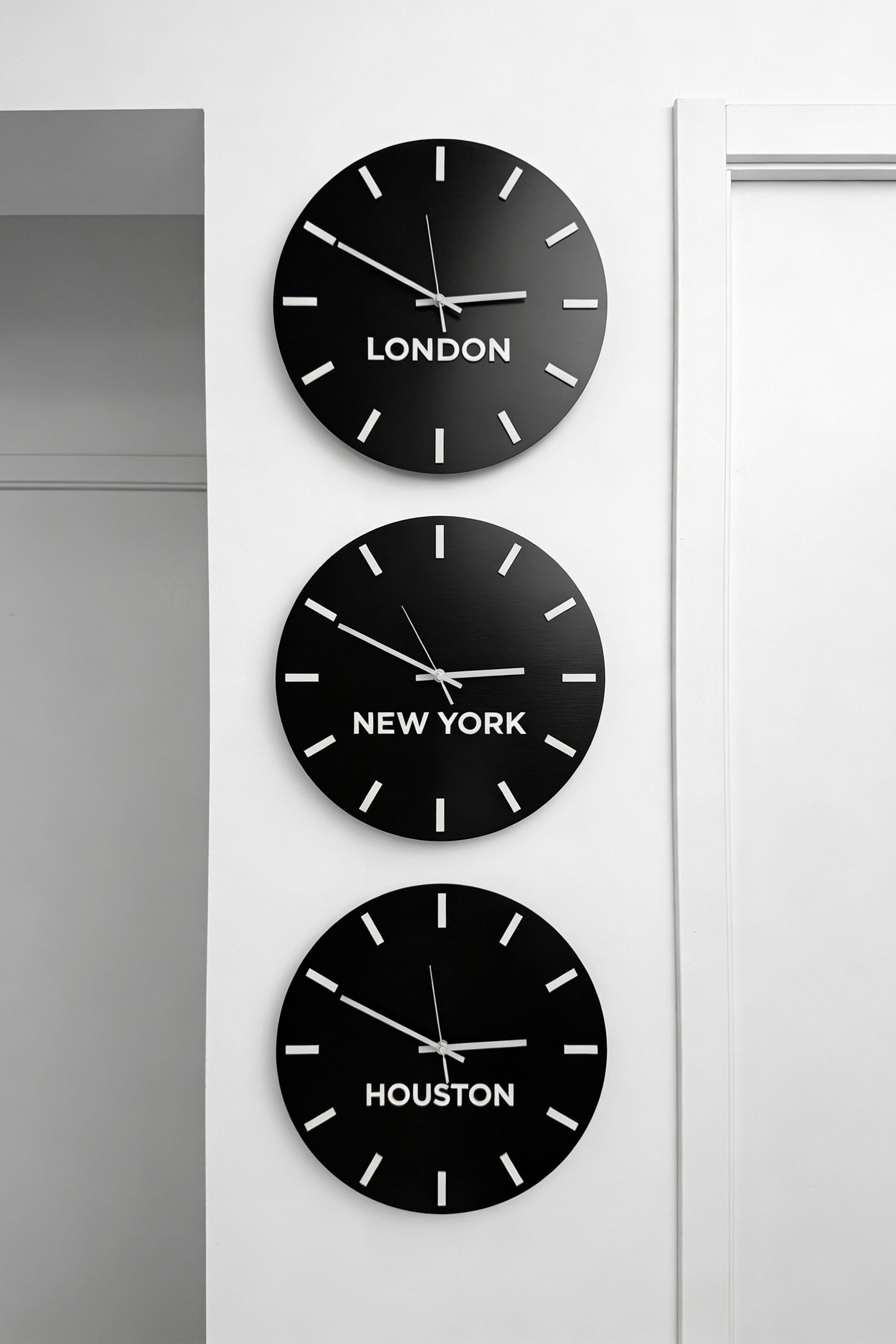 Brushed black personalized world time zone clock with white acrylic glass city name plates by ALUMADESIGNCO, premium wall décor for studios, offices, hotels, and corporate interiors