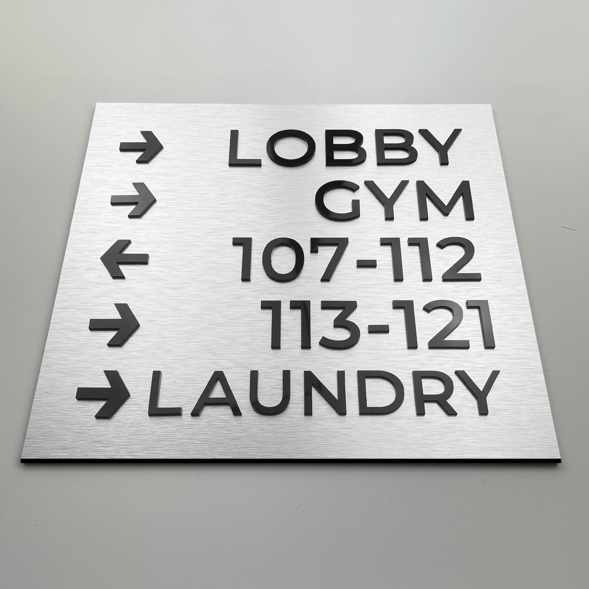 Elegant aluminium wayfinding sign directing to lobby area in a luxury hotel setting