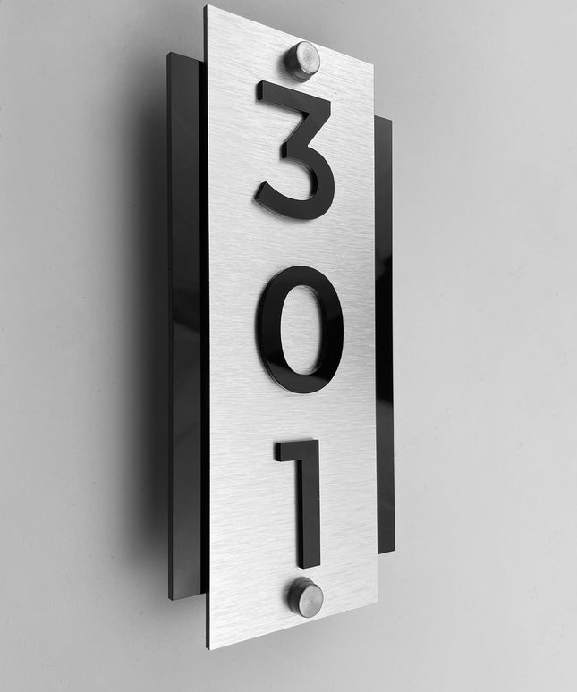 Vertical hotel room number sign by ALUMADESIGNCO with silver metal plaque and raised acrylic numbers, modern standoff door signage for hotel corridors and apartments