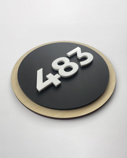 Round wood and acrylic hotel room number sign by ALUMADESIGNCO featuring birch plywood base with raised black acrylic numbers, modern Scandinavian door plaque for hotel corridors and apartments