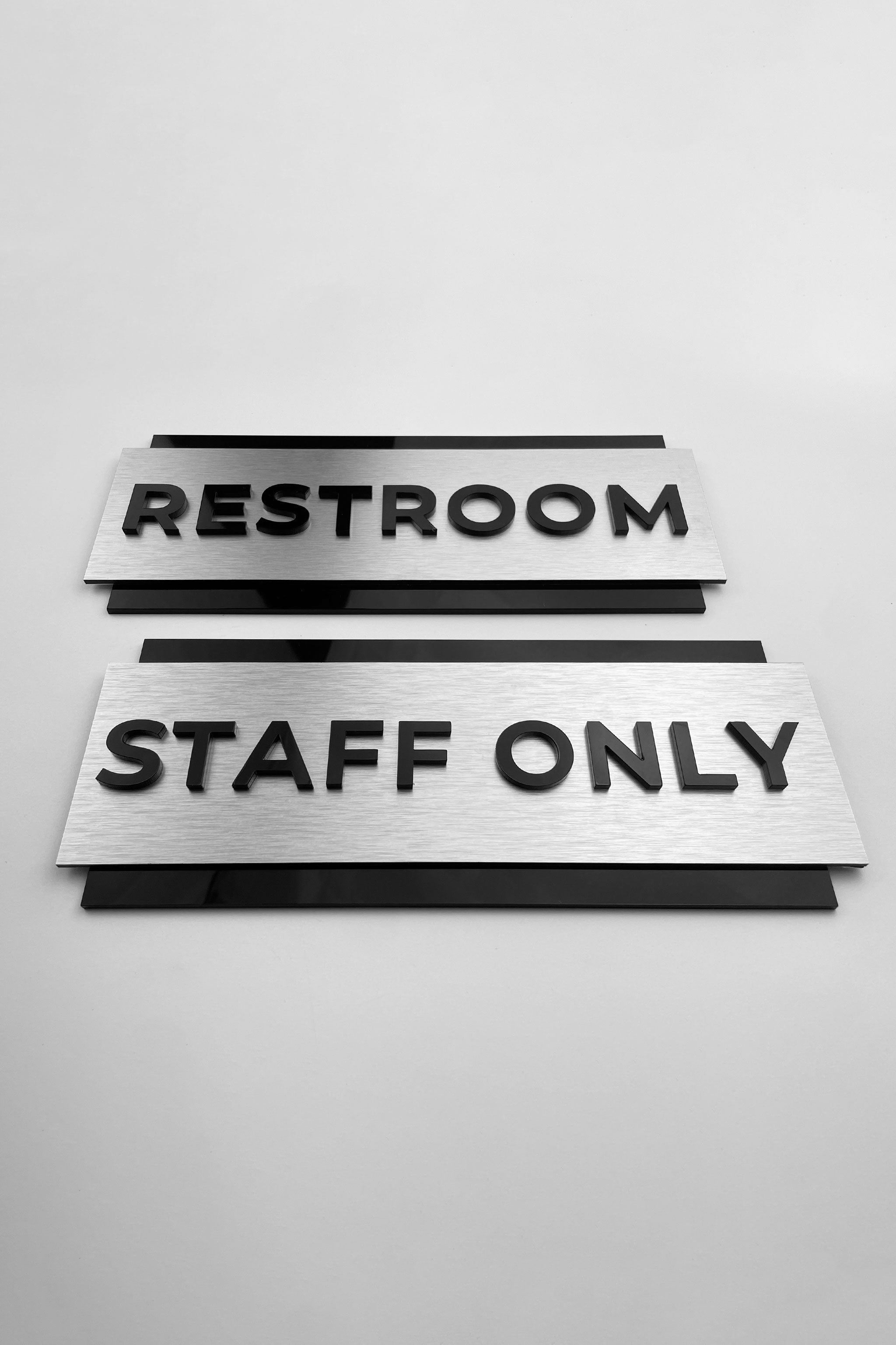Premium custom door sign by ALUMADESIGNCO featuring brushed silver plaque and black acrylic text, modern signage for offices, restrooms, and hotel interiors