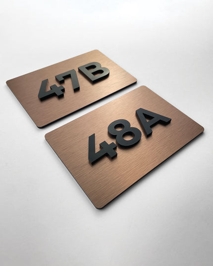 Modern brushed bronze room number sign by ALUMADESIGNCO combining bronze metal panel and acrylic numbers, stylish door signage for contemporary interiors