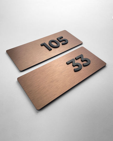 Brushed bronze apartment door number sign Classic Design by ALUMADESIGNCO featuring metal plaque and acrylic numbers, elegant signage for apartment interiors and hotel corridors