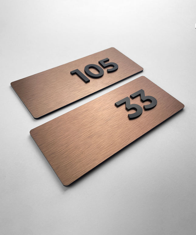Brushed bronze apartment door number sign Classic Design by ALUMADESIGNCO featuring metal plaque and acrylic numbers, elegant signage for apartment interiors and hotel corridors