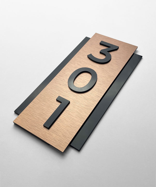Vertical brushed bronze room number plaque by ALUMADESIGNCO featuring bronze aluminum panel and raised black acrylic glass numbers, modern hotel door signage for corridors and apartments