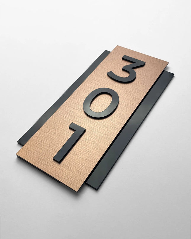 Vertical brushed bronze room number plaque by ALUMADESIGNCO featuring bronze aluminum panel and raised black acrylic glass numbers, modern hotel door signage for corridors and apartments