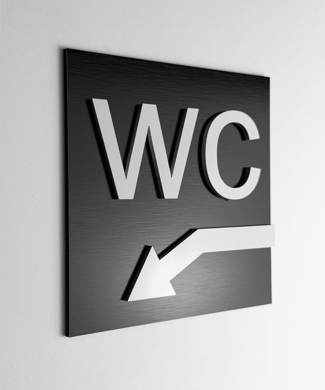 ALUMADESIGNCO WC arrow sign down left with modern directional design, premium restroom wayfinding signage for offices, hotels, cafés, and commercial interiors