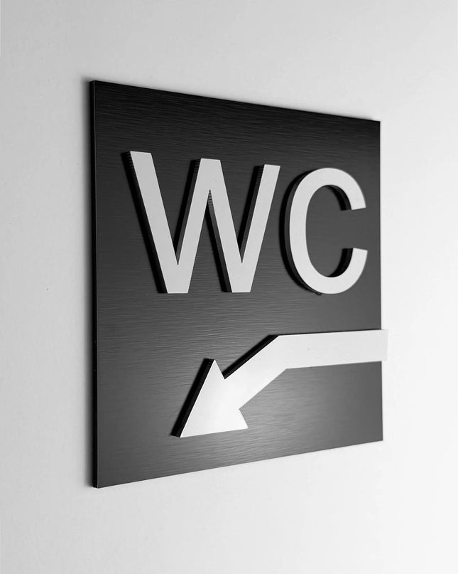 ALUMADESIGNCO WC arrow sign down left with modern directional design, premium restroom wayfinding signage for offices, hotels, cafés, and commercial interiors