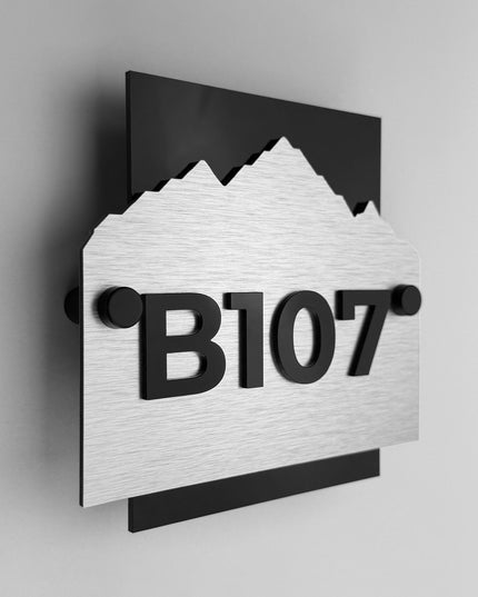 Custom Alpine hotel wall number sign by ALUMADESIGNCO featuring brushed silver metal plaque and black acrylic numbers, modern hotel room door signage for corridors and hospitality interiors