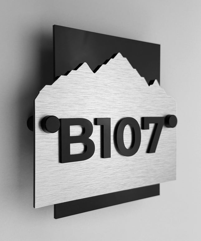 Custom Alpine hotel wall number sign by ALUMADESIGNCO featuring brushed silver metal plaque and black acrylic numbers, modern hotel room door signage for corridors and hospitality interiors