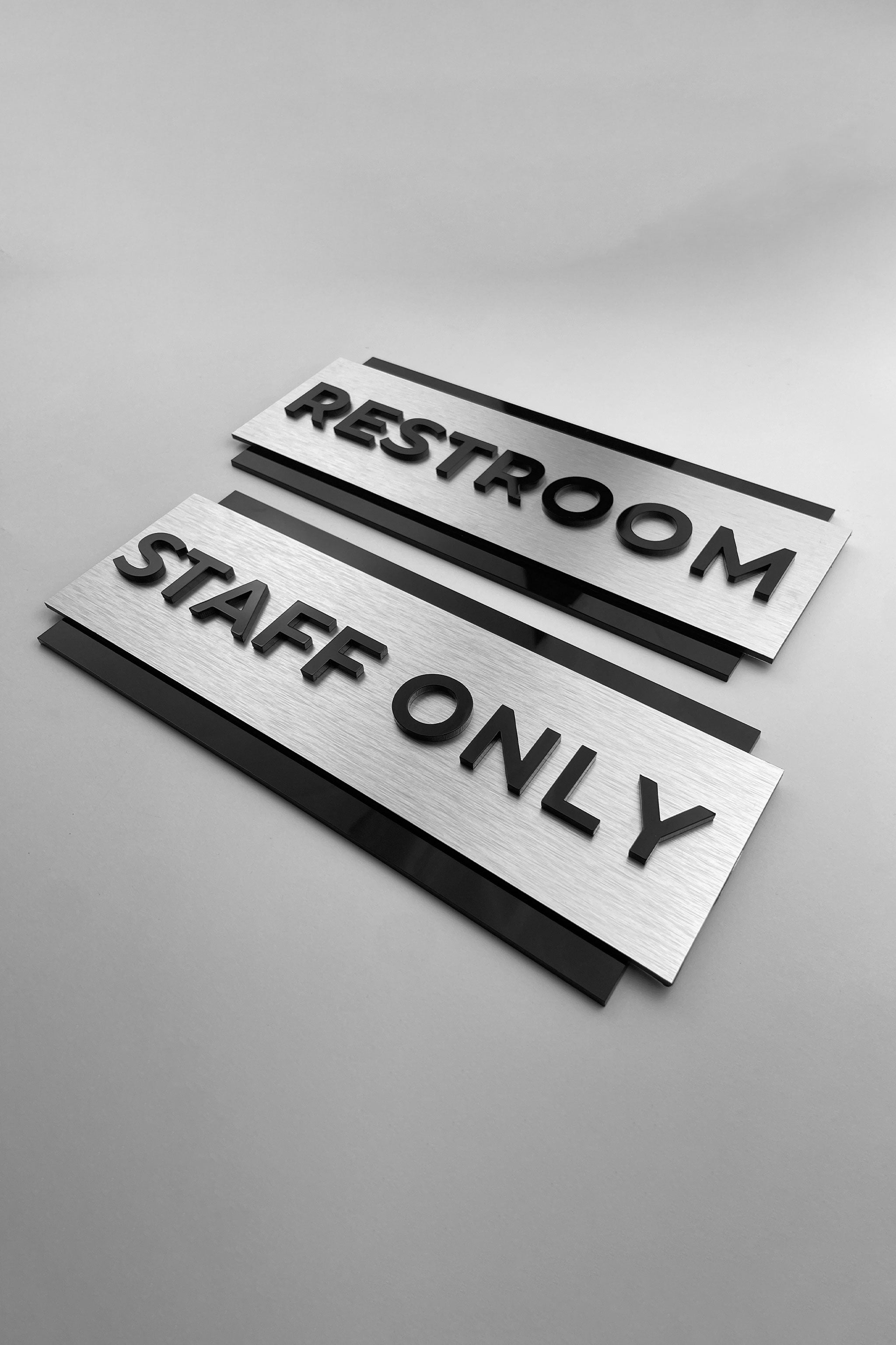 Custom brushed silver and black acrylic door sign by ALUMADESIGNCO for staff only, office, restroom, and facility signage, modern wayfinding plaque for interiors