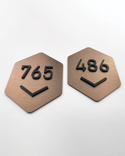 Brushed bronze hexagon room number sign by ALUMADESIGNCO featuring metal plaque and acrylic numbers, modern door signage for hotel rooms and apartment interiors