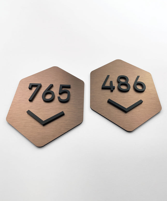 Brushed bronze hexagon room number sign by ALUMADESIGNCO featuring metal plaque and acrylic numbers, modern door signage for hotel rooms and apartment interiors