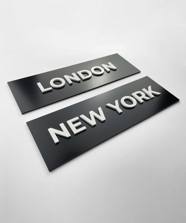 Modern black door name sign by ALUMADESIGNCO combining sleek black plaque and white acrylic text, elegant signage for offices, hotels, and interior spaces