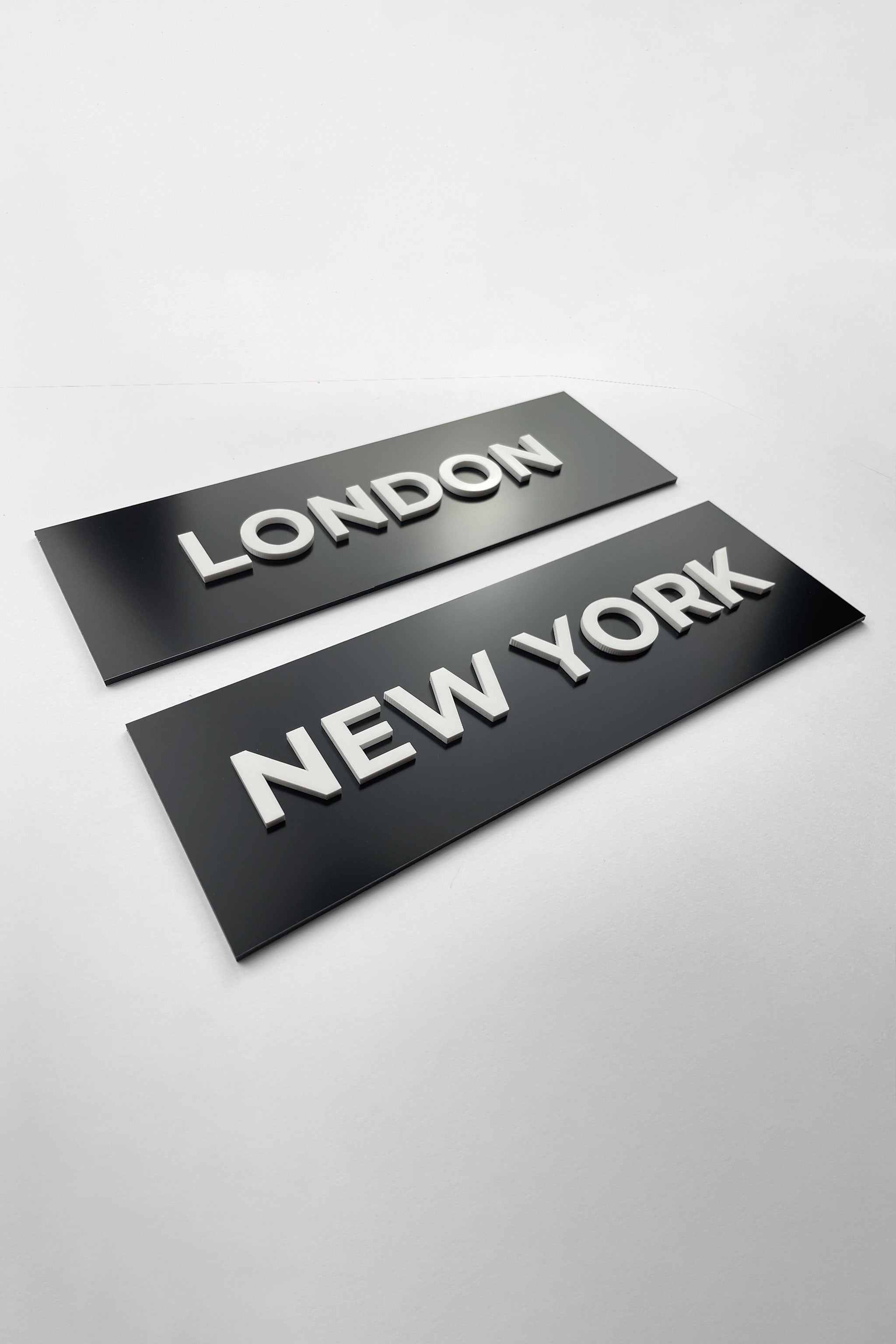 Modern black door name sign by ALUMADESIGNCO combining sleek black plaque and white acrylic text, elegant signage for offices, hotels, and interior spaces
