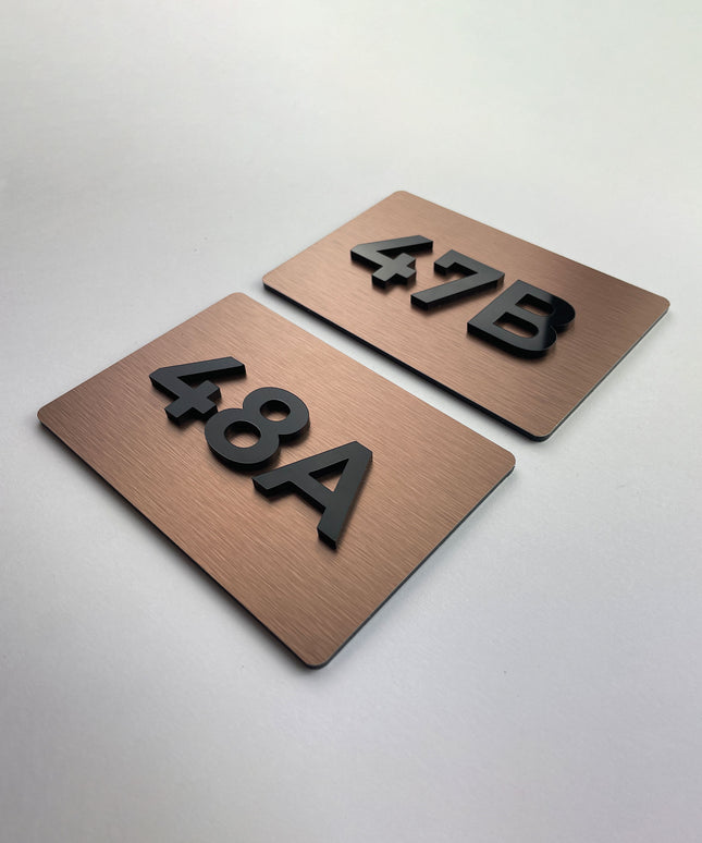 Brushed bronze door number sign by ALUMADESIGNCO featuring metal plaque and acrylic numbers, elegant signage for hotel rooms and apartment interiors