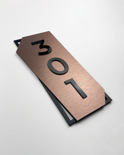 Vertical brushed bronze hotel room number sign by ALUMADESIGNCO featuring bronze aluminum base and black acrylic numbers, modern door number signage for hotel corridors and apartment buildings