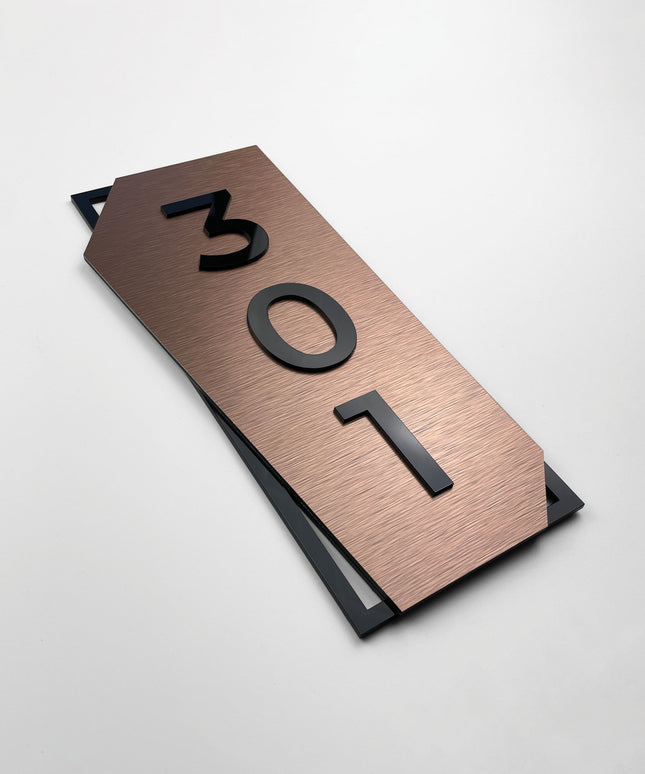 Vertical brushed bronze hotel room number sign by ALUMADESIGNCO featuring bronze aluminum base and black acrylic numbers, modern door number signage for hotel corridors and apartment buildings