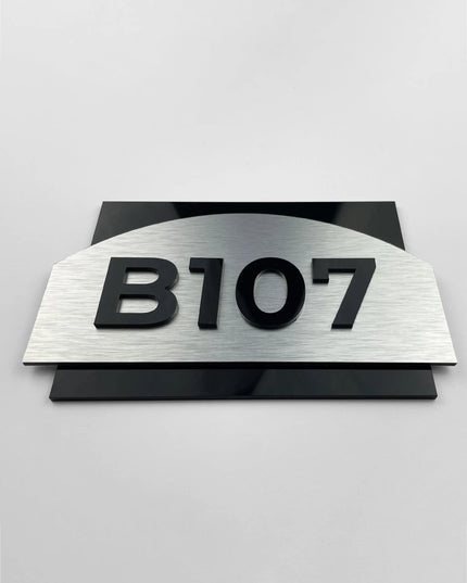 Black acrylic apartment numbers on a brushed silver door plate
