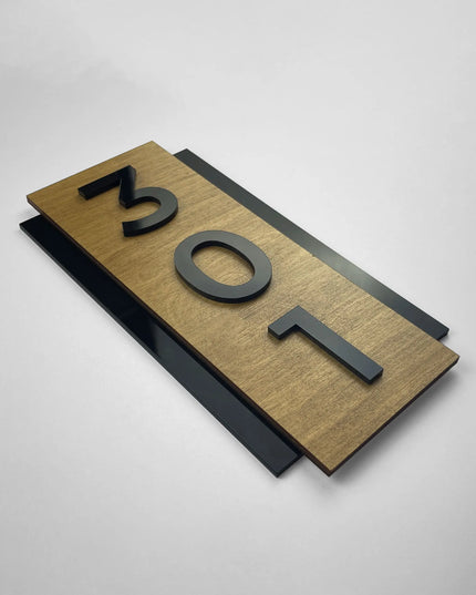 Hölzernes Hotel-Zimmernummernschild im Hochformat mit plastischen schwarzen Acrylzahlen und einer personalisierten Nummer für Gästezimmer.