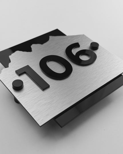 Modern Alpine hotel room number sign by ALUMADESIGNCO featuring brushed silver aluminum panel and raised black acrylic numbers, standoff mounted wall signage for hotel corridors and apartments