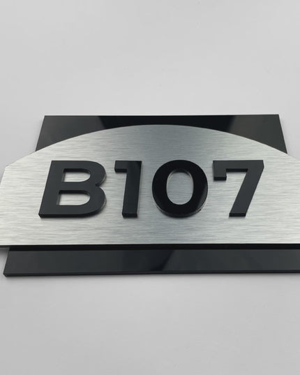 Premium Flow apartment door number sign by ALUMADESIGNCO featuring brushed silver aluminum and black acrylic glass numbers, elegant door plaque for interiors