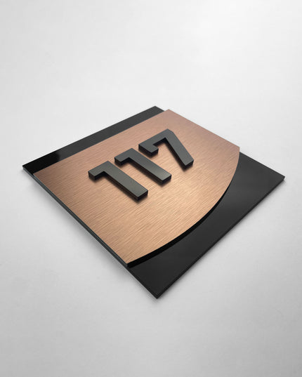 Modern 3D layered hotel room number sign by ALUMADESIGNCO combining bronze metal panel and black acrylic numbers, stylish door signage for hospitality interiors